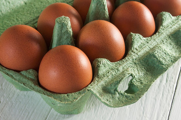 Large brown chicken eggs in green carton box. Close-up.