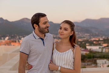 Young couple smiling in front of cityscape and mountain view