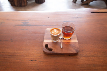 Piccolo Latte art in small glass with hot tea on wooden desk