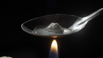Cooking Heroin on Spoon Close Up on Candle. a close up view of a spoon cooking heroin
