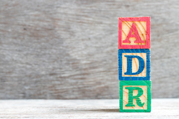 Color letter block in word ADR (Abbreviation of adverse drug reaction) on wood background