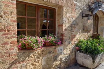 Fototapeta na wymiar Old house decorated with flowers in Monteriggioni, Tuscany, Italy