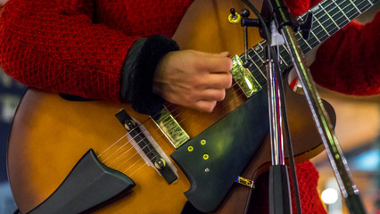 Close up of singer while playing guitar, lights and glitters in the background.