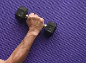  Asian man lifting a dumbbell in fitness gym, purple blue floor exercise mat background.