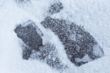 Close-up of abstract figures on snow on ice in the winter, viewed from above. Simple and minimal full frame abstract background. Copy space.