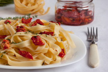Fettuccine pasta with sun-dried tomatoes and fresh herbs. Close up.