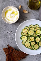 Grilled zucchini salad with beans, yogurt dip and rye sliced bread. Vegetarian food. Top view with copy space.
