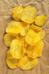 Flat potato chips on wrapping paper background, top view, vertical image