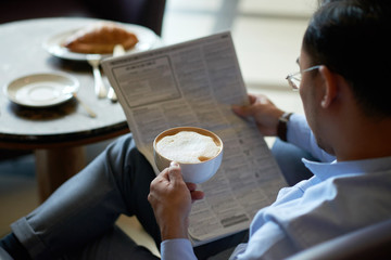 Businessman enjoying latte and newspaper