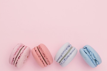 Pink, blue, red and lavender macaroons on the pastel pink background. Holidays concept with sweet.