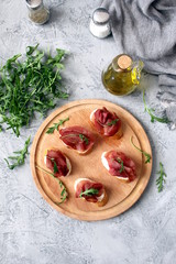 Canape or crostini with toasted baguette, light cheese, bresaola and arugula on wooden board. Diet food. Iron food.