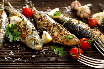 Fototapeten Gebratener Fisch mit Zusatz von Kräutern, Gewürzen und Zitronenscheiben auf Holzhintergrund. © zi3000
