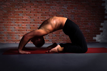  Young man doing the pose of yoga Kapotasana