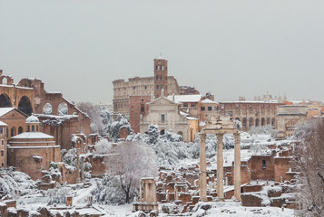 Frozen Rome. View of Roman Forum ancient ruins and Coliseum covered by snow