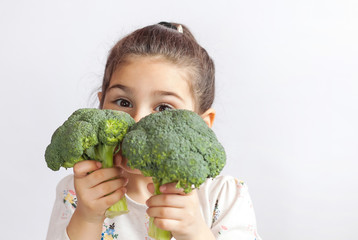 Selamat tersenyum anak perempuan makan sayur.  Makanan sehat.  Brokoli segar.