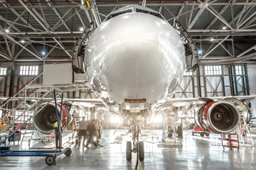 Passenger aircraft, nose close up. Maintenance of engine and fuselage repair in airport hangar - obrazy, fototapety, plakaty