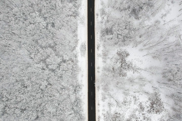 Winter view of a road in the middle of the forest covered with snow