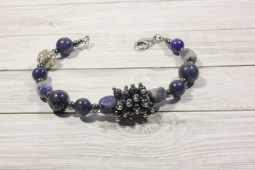 Handmade bracelet with semi-precious natural stones on a light background. Lapis lazuli, hematite,...
