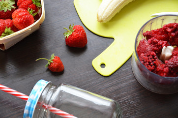 Strawberry and banana smoothie in the jar. Ingredients for making smoothies strawberry banana, frozen berries in a blender on a dark black wooden background.