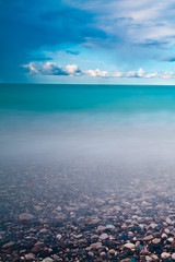 Beach pebbles smooth blue sea under blue sky