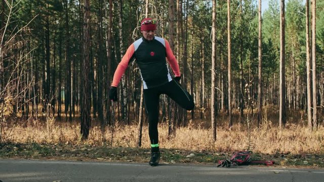 Training an athlete on the roller skaters. Biathlon ride on the roller skis with ski poles, in the helmet. Autumn workout. Roller sport. Adult man riding on skates. The athlete does the workout. Slow