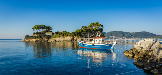 Fototapeta na wymiar Blue boat parked in the Laganas dock with the Cameo island in the back