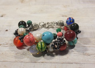Handmade bracelet with semi-precious natural stones on a light background. Turquoise, coral, garnet, silver accessories.