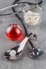 close-up of a large white tablet on a metal spoon on background a stethoscope and medication syrup