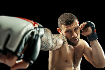 MMA. professional boxer boxing isolated on black studio background. fit muscular caucasian athlete...