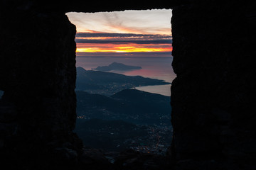 panorama of the Sorrento peninsula and of Capri at sunset seen through a window of a ruin