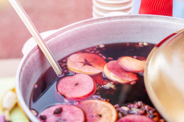 Mulled wine prepared in iron pot at city street fair. Traditional christmas and new year alcohol drink - hot wine. Stall with drinks in town at winter holiday fest