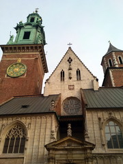 Fototapeta premium The view of the pilgrim from below on the beauty, uniqueness and greatness of the medieval Catholic churches in Krakow against the background of the cloudy blue winter sky.