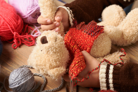 Child boy is learning to knit. Colorful wool yarns are on the wooden table. Hand closeup.
