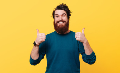 Portrait of happy man showing thumbs up over yellow background