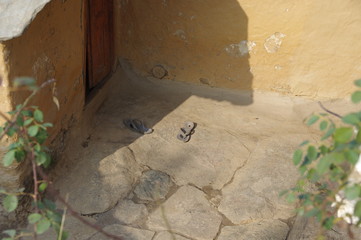 Slippers on stone floor in front of hut