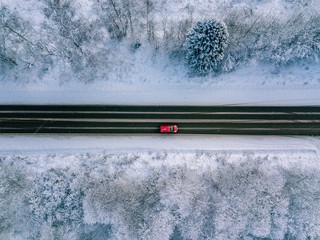 Aerial view of country road going through the beautiful snow covered landscape.