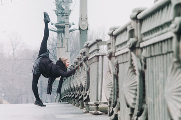 Gymnast doing stretching on a bridge in the city, urban style