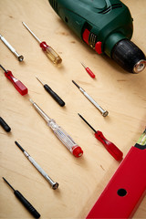 pattern background of various screwdrivers and a drill with a spirit level on a wooden work table