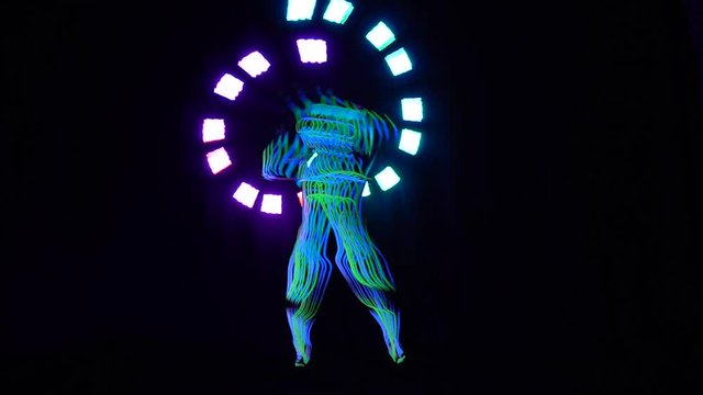 A man in a glowing suit, performing the neon show in the dark