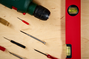 pattern background of various screwdrivers and a drill with a spirit level on a wooden work table