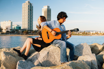 Coverband couple of musicians play acoustic guitar and sing near the beach. Sea on background