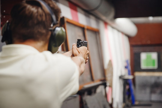 Shooting range gun. Man shoots pistol in noise protection headphones