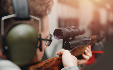 Fototapeta na wymiar Man shoots pistol in noise protection headphones. Shooting range gun