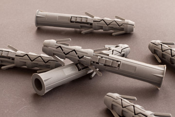 Clear pfoto of Gray plastic wall plugs and building anchors are lying on a smooth gray surface....