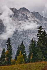 The gloomy rocky top of the mountain, under thunderclouds, fir trees, autumn landscape.