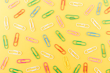 Background made from colored paper clips on the orange base