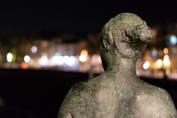 Imagen nocturna de escultura de mujer de espaldas mirando a la costa de Sitges