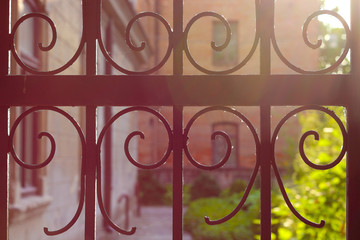 Fragment of an old wrought iron lattice gate (fence) at sunset (backlight)