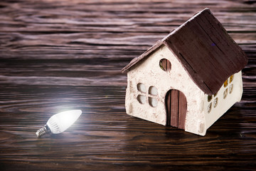 Led lamps lie near the house layout on a wooden background
