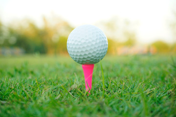 Blurred golf ball on tee in beautiful golf course at sunset background.